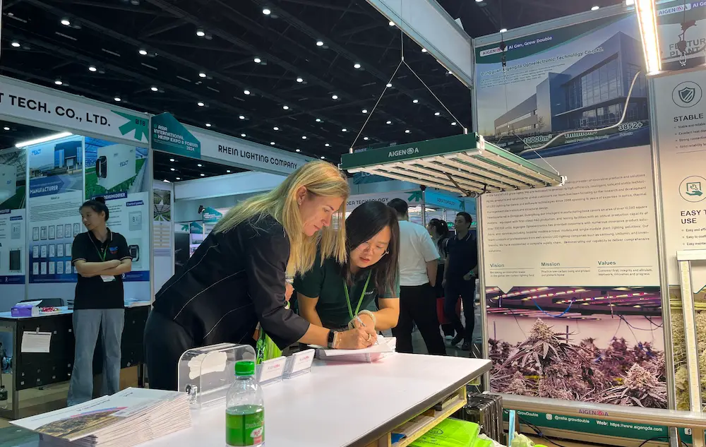 Prospective client discussing project details and signing an inquiry at the AIGENGDA exhibition counter.